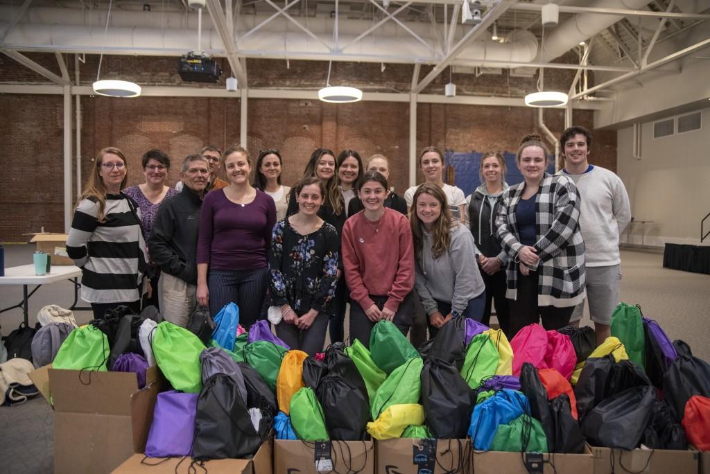 A group of 学生 pose together for a Service-Learning program where they prepared harm-reduction bags for the Maine Correctional Facility